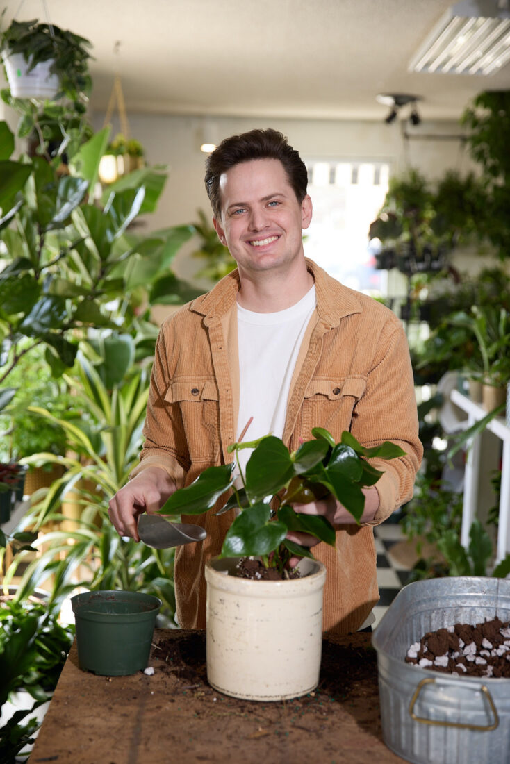 a portrait of a man with plants around him