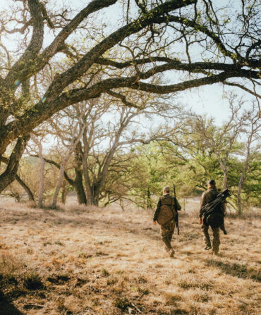 Two men walk in a scrubby landscape