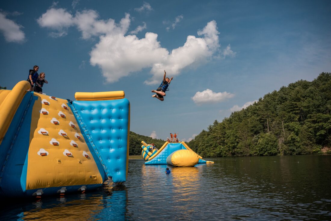 Kids jump from an inflatable into a lake