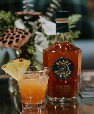 A bourbon cocktail with a pineapple slice