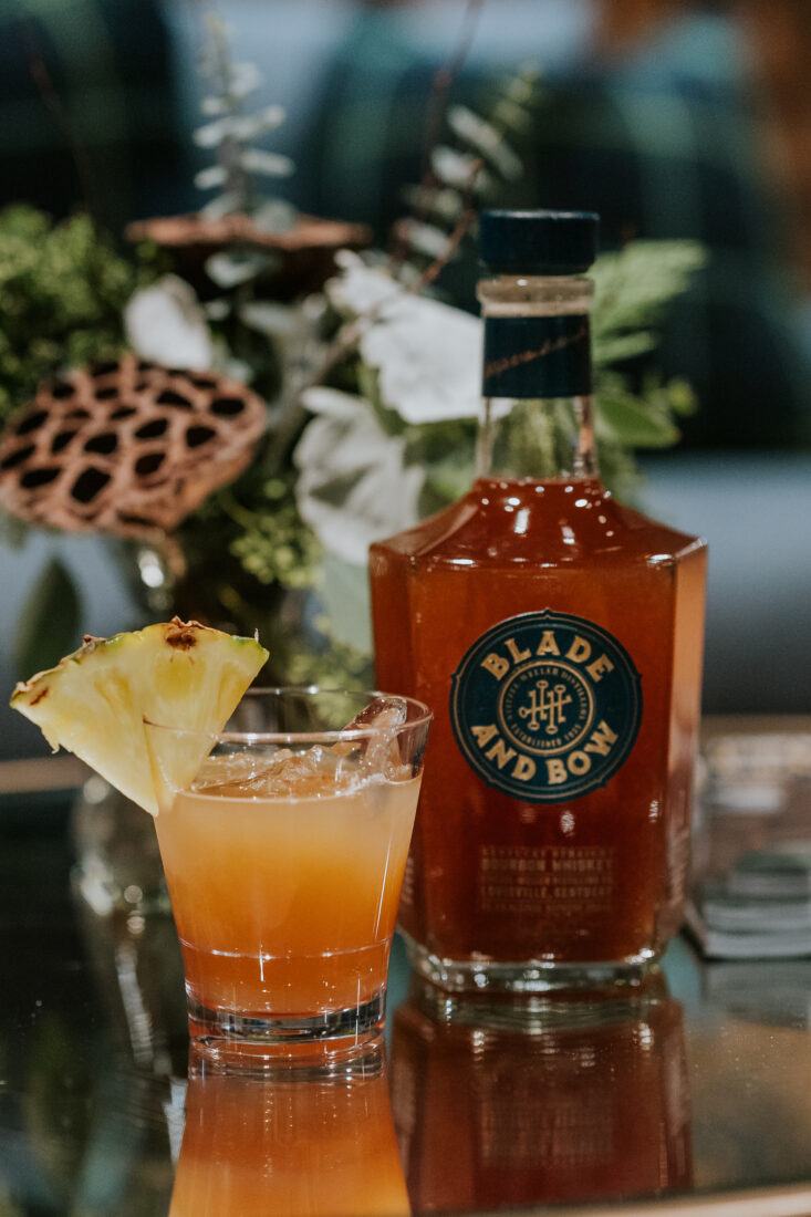 A bourbon cocktail with a pineapple slice