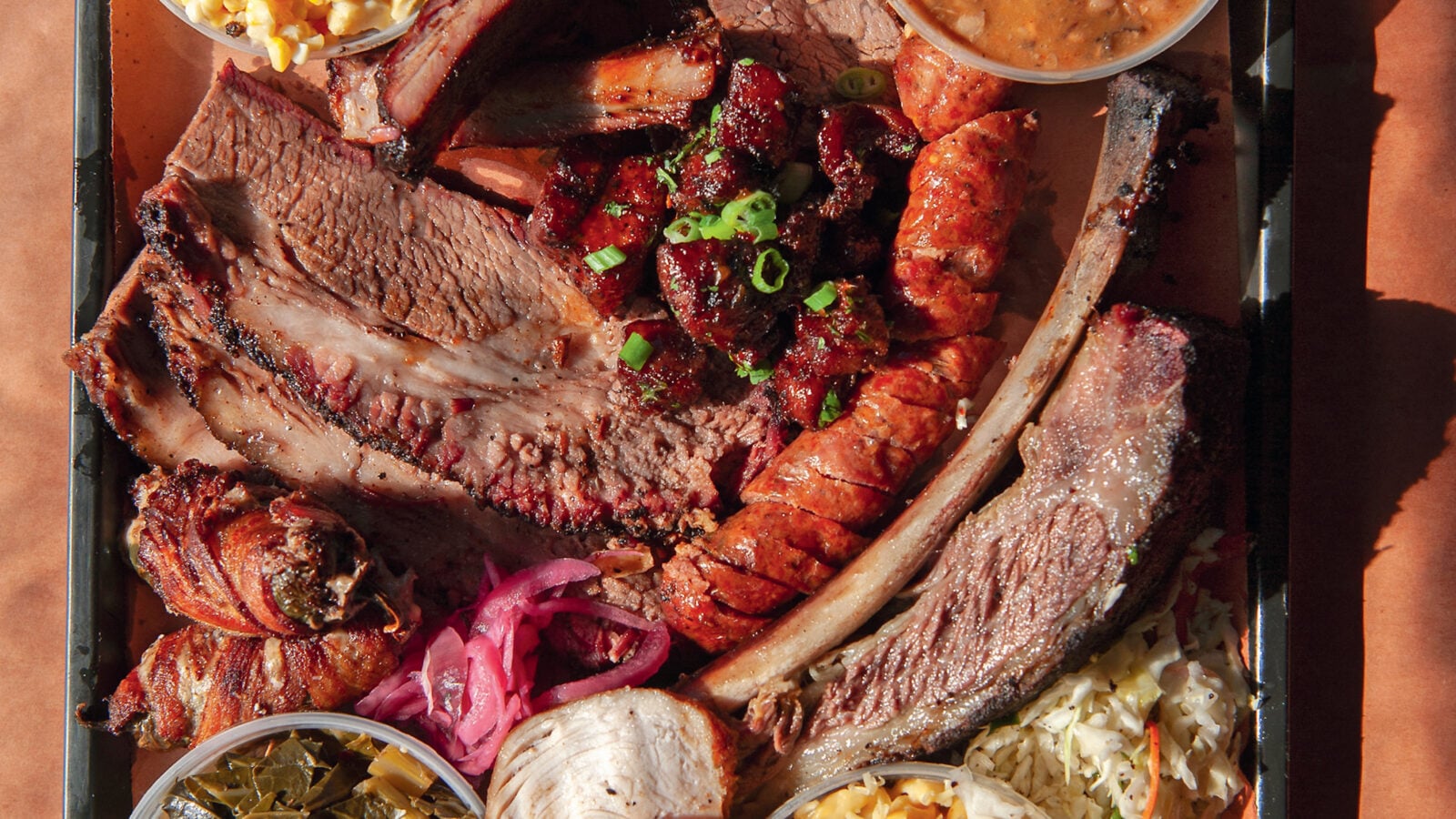 A tray of brisket, pineapple sausage, smoked turkey, corn salad, green chile mac and cheese, and more.