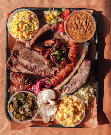 A tray of brisket, pineapple sausage, smoked turkey, corn salad, green chile mac and cheese, and more.