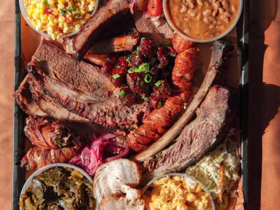 A tray of brisket, pineapple sausage, smoked turkey, corn salad, green chile mac and cheese, and more.