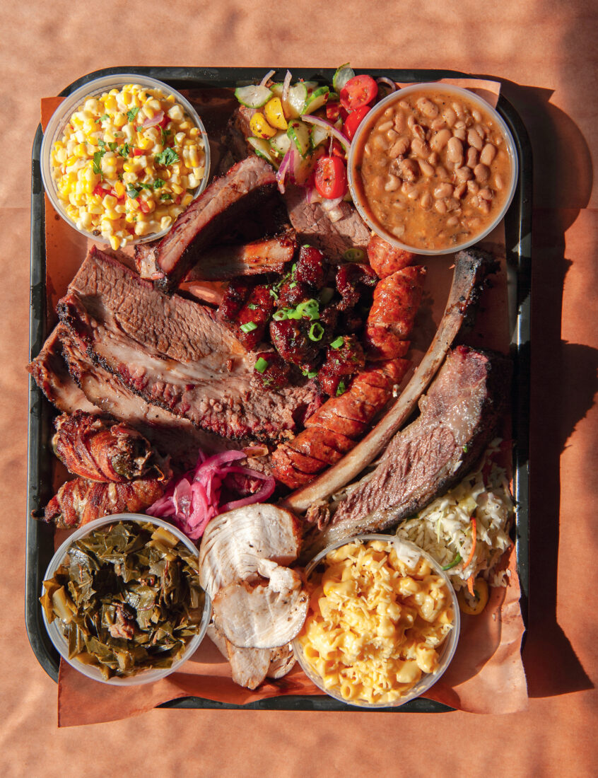 A tray of brisket, pineapple sausage, smoked turkey, corn salad, green chile mac and cheese, and more.