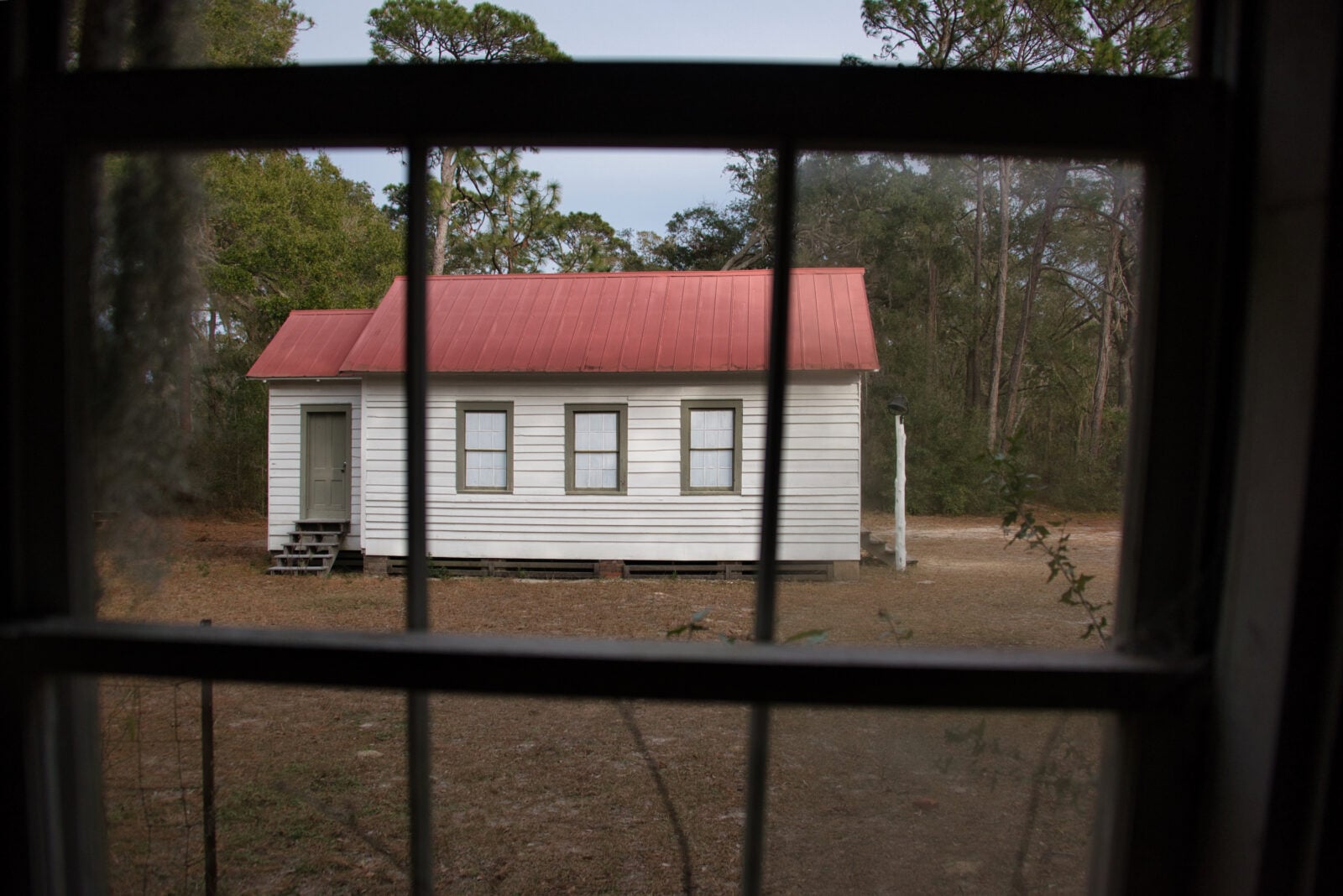 A white house with a red roof through a window