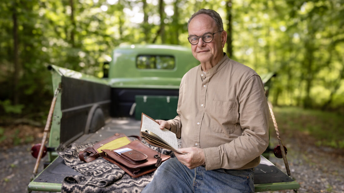 A man sits on a truck bed with a journal