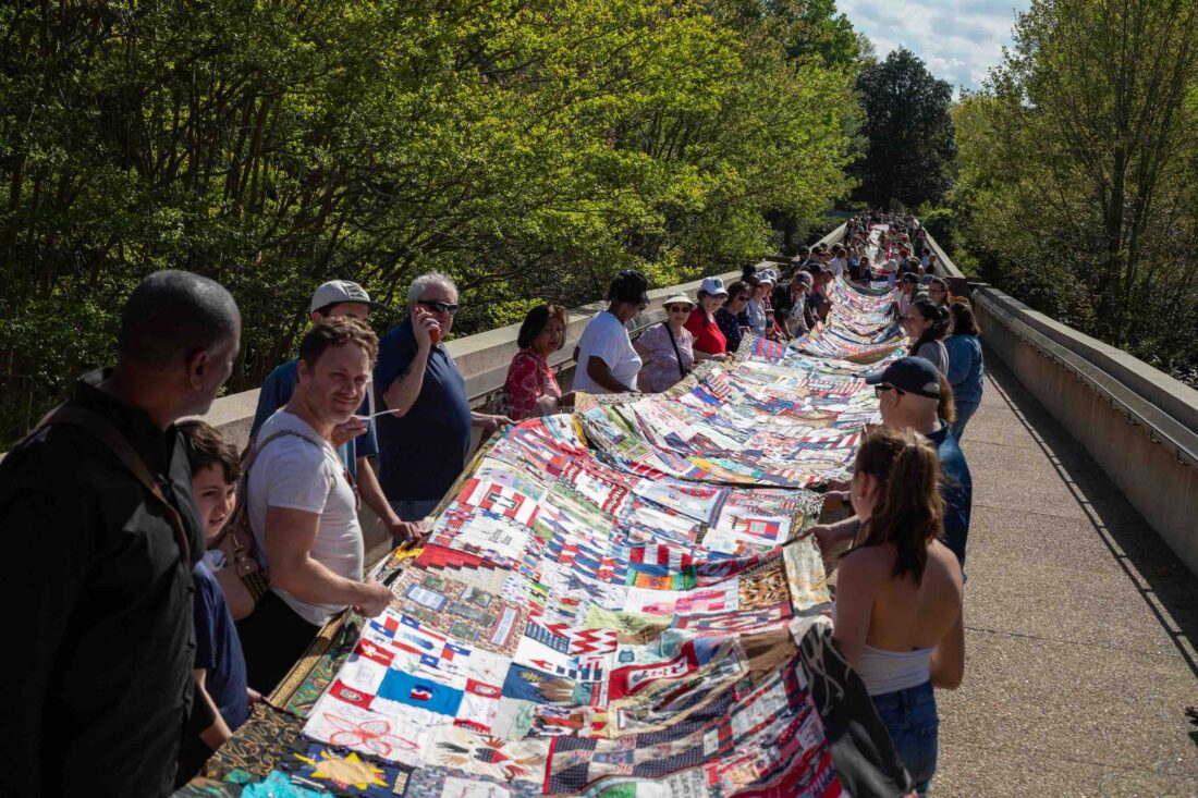 People hold a long quilt outside