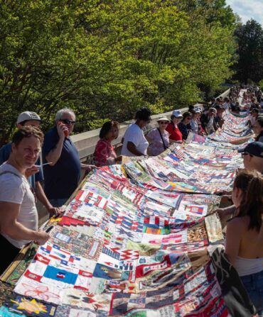 People hold a long quilt outside