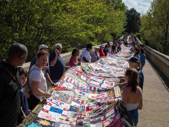 People hold a long quilt outside