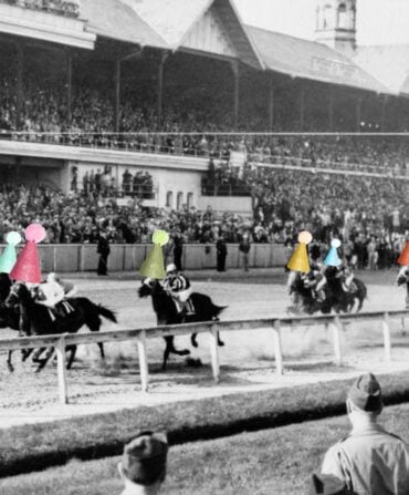 A black and white photo of horses on a racetrack with party hats
