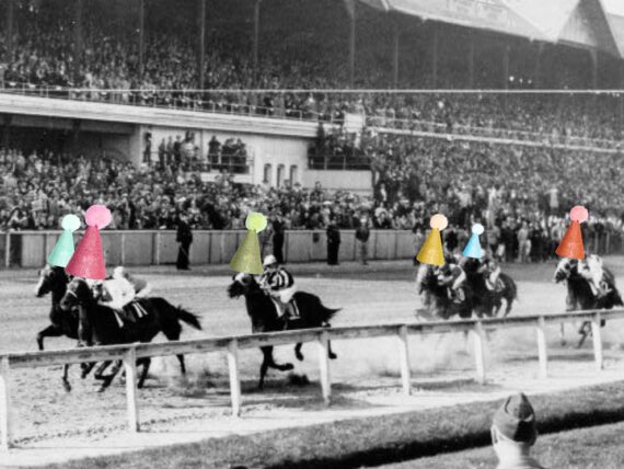 A black and white photo of horses on a racetrack with party hats