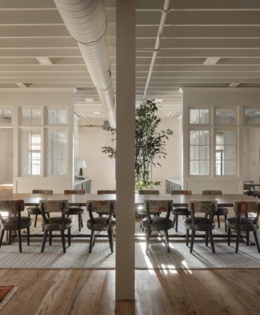 A large table with multiple chairs in a open concept office