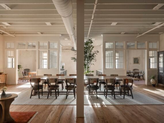 A large table with multiple chairs in a open concept office