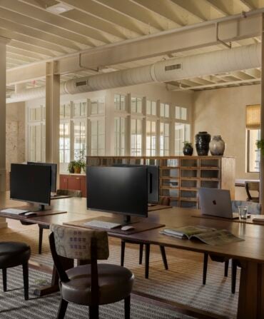 A large table with monitors and desks in a open concept office