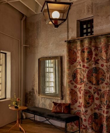 A hallway bench against a wall with a mirror and curtain