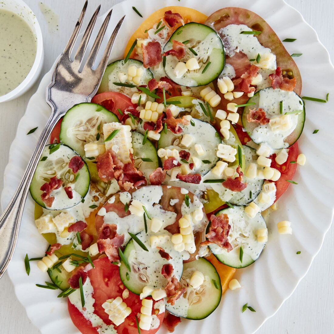salad with tomatoes, corn, cucumber and buttermilk dressing on a serving platter