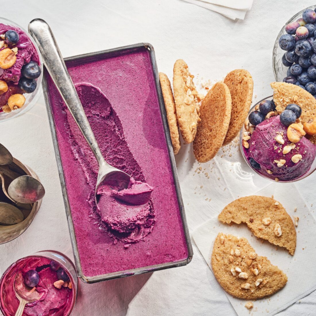 Image of bluberry ice cream in a tin with corn cookies on the side