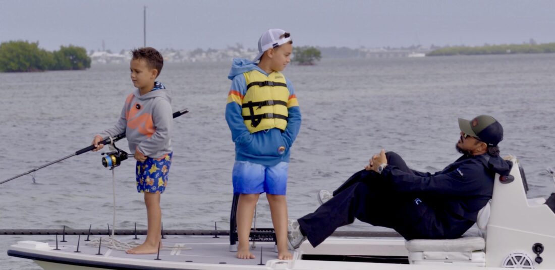 Boys on a boat hold a fishing pole