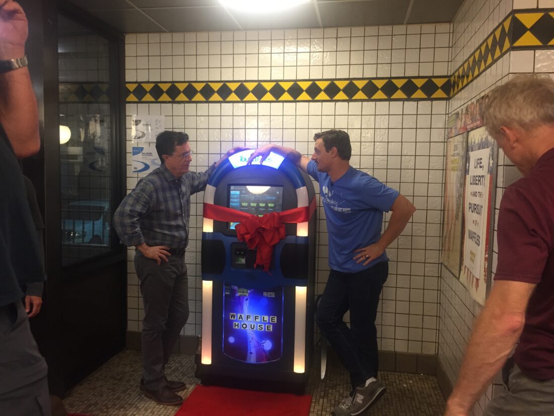 Two men stand by a waffle house jukebox