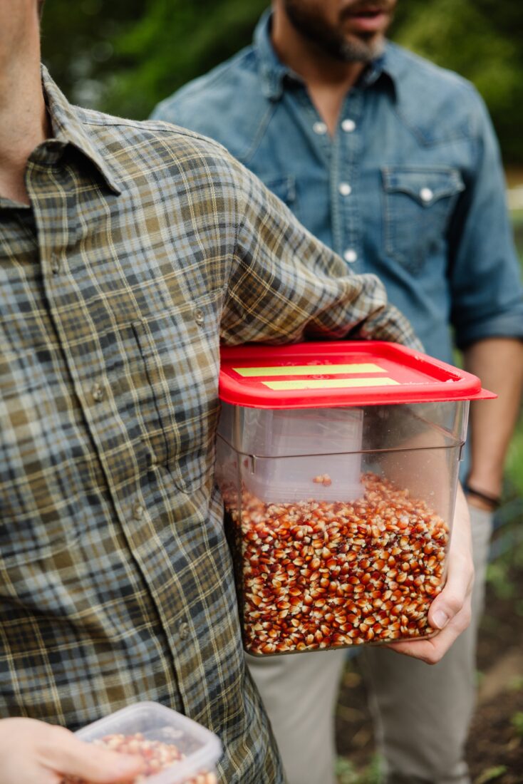 image of man holding red container of corn kernels