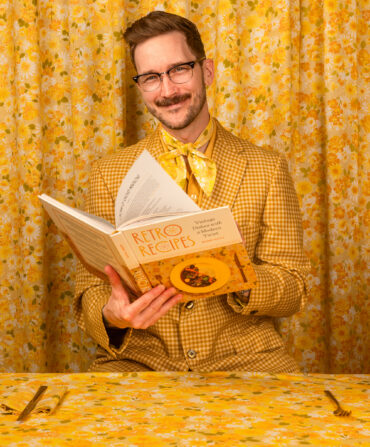 A man in a yellow suit with a cookbook