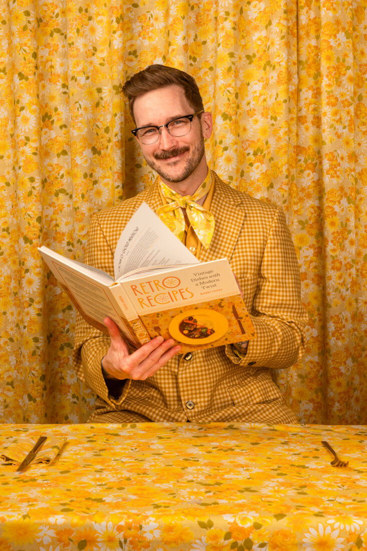 A man in a yellow suit with a cookbook