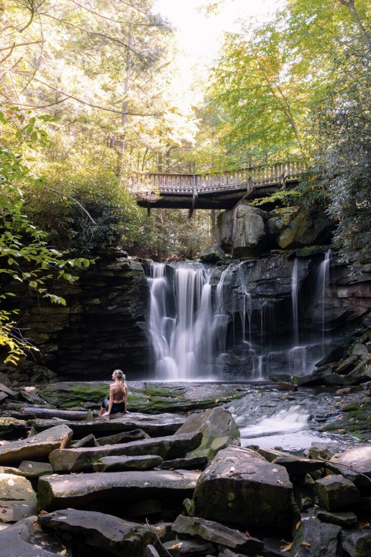A woman sits by a waterfall