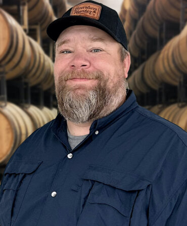 A portrait of a man with bourbon barrels
