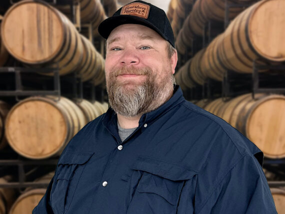 A portrait of a man with bourbon barrels