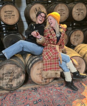 Two women in front of bourbon barrels