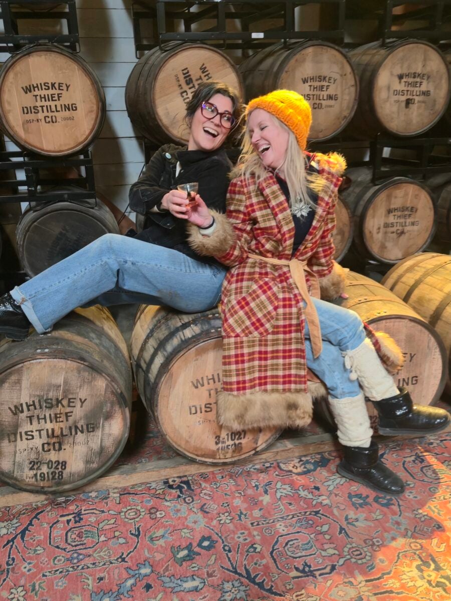 Two women in front of bourbon barrels