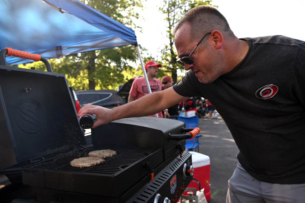 Image of a Carolina Hurricanes fan tailgating and grilling before a game.