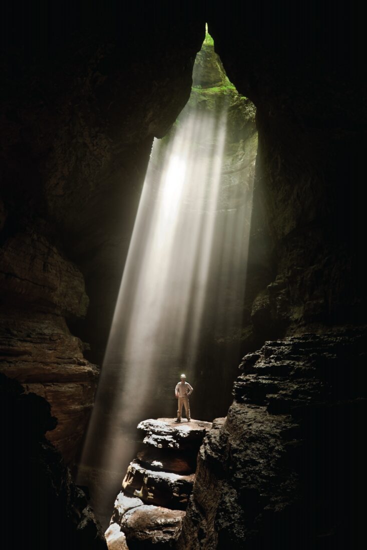 A man inside a cave with a shaft of light