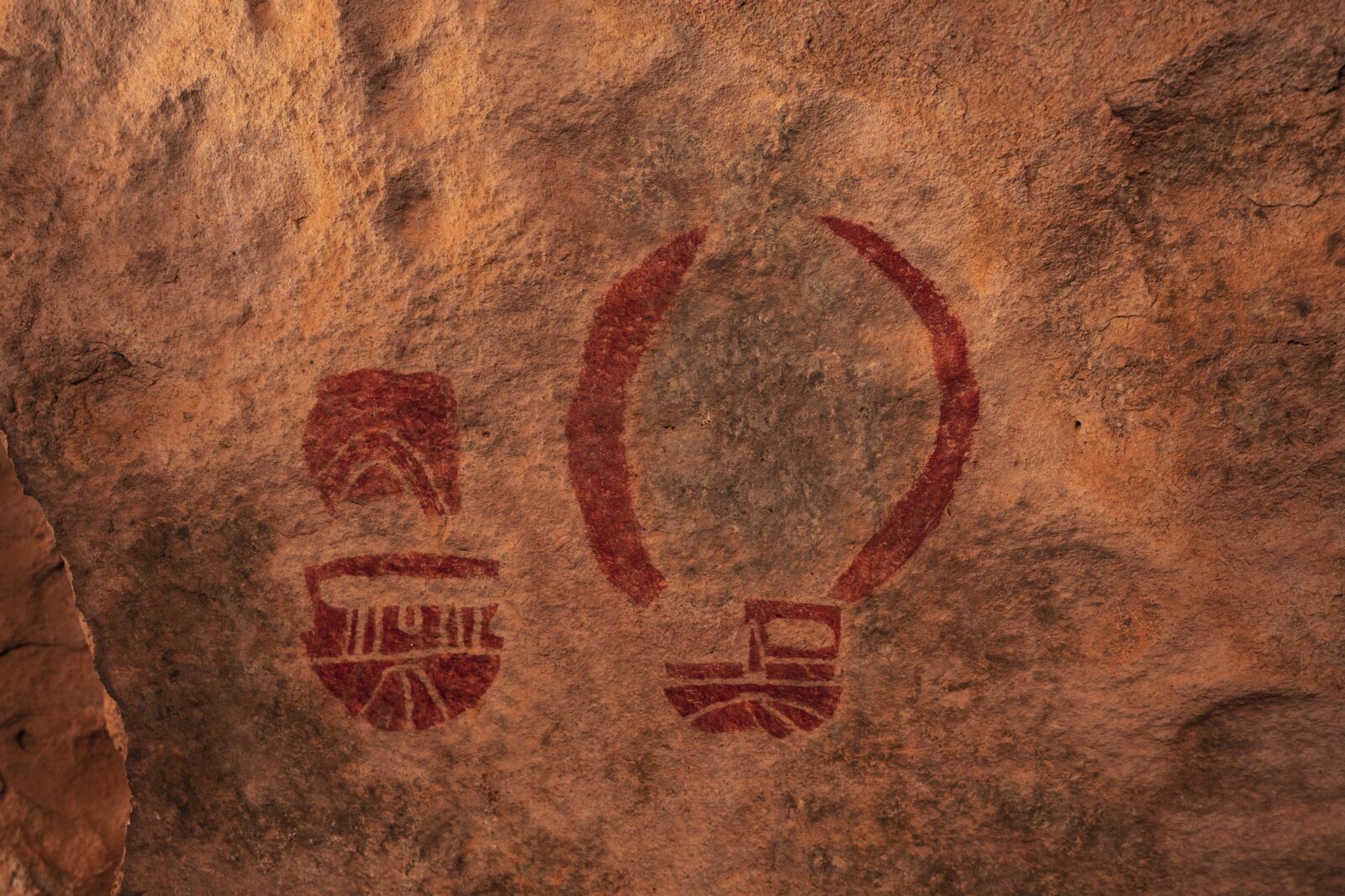 mask pictographs on a rock wall