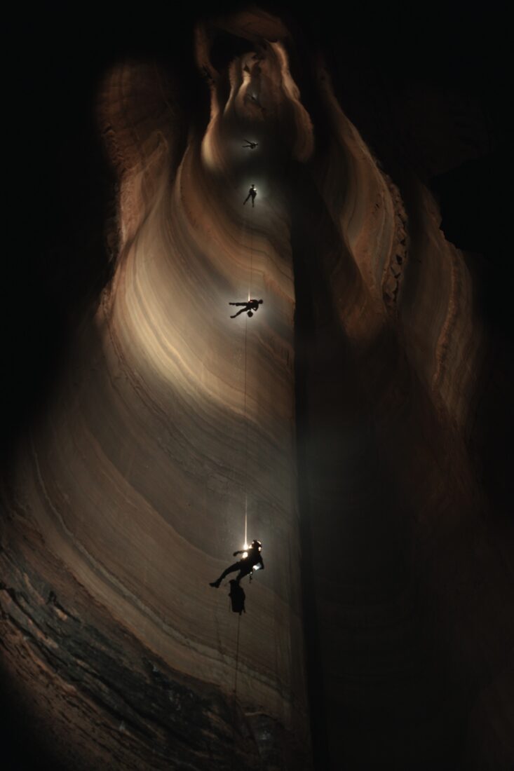 A person rappels down a cave