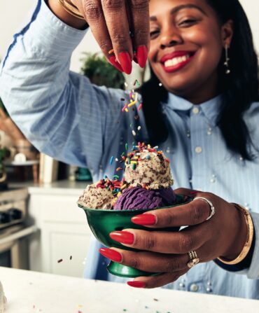 A woman sprinkles sprinkles onto ice cream