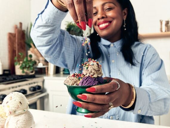 A woman sprinkles sprinkles onto ice cream