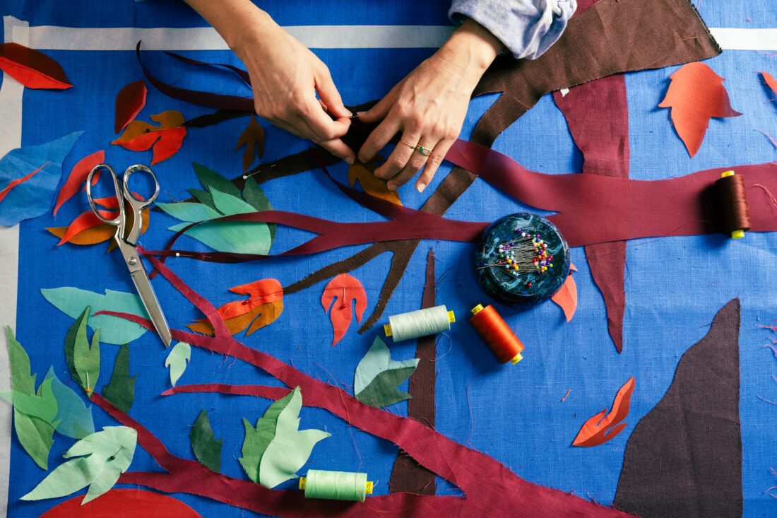 Hands pin pieces of a tree textile collage in place