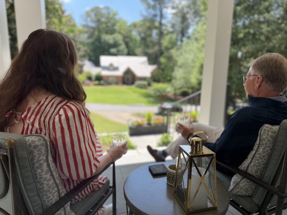 Two people sip bourbon on a porch