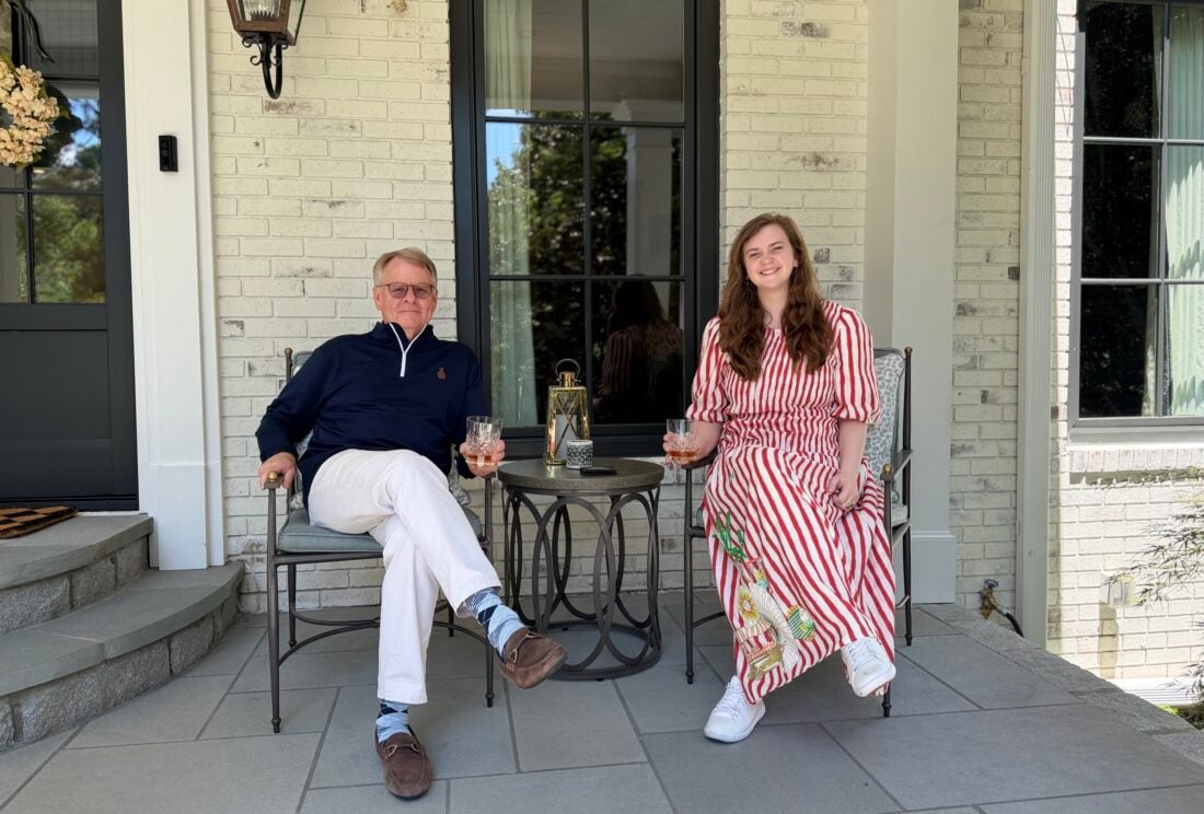 A man and woman sit on a porch