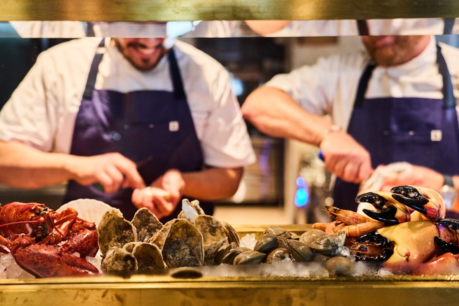 image of two chefs behind a raw bar counter preparing seafood