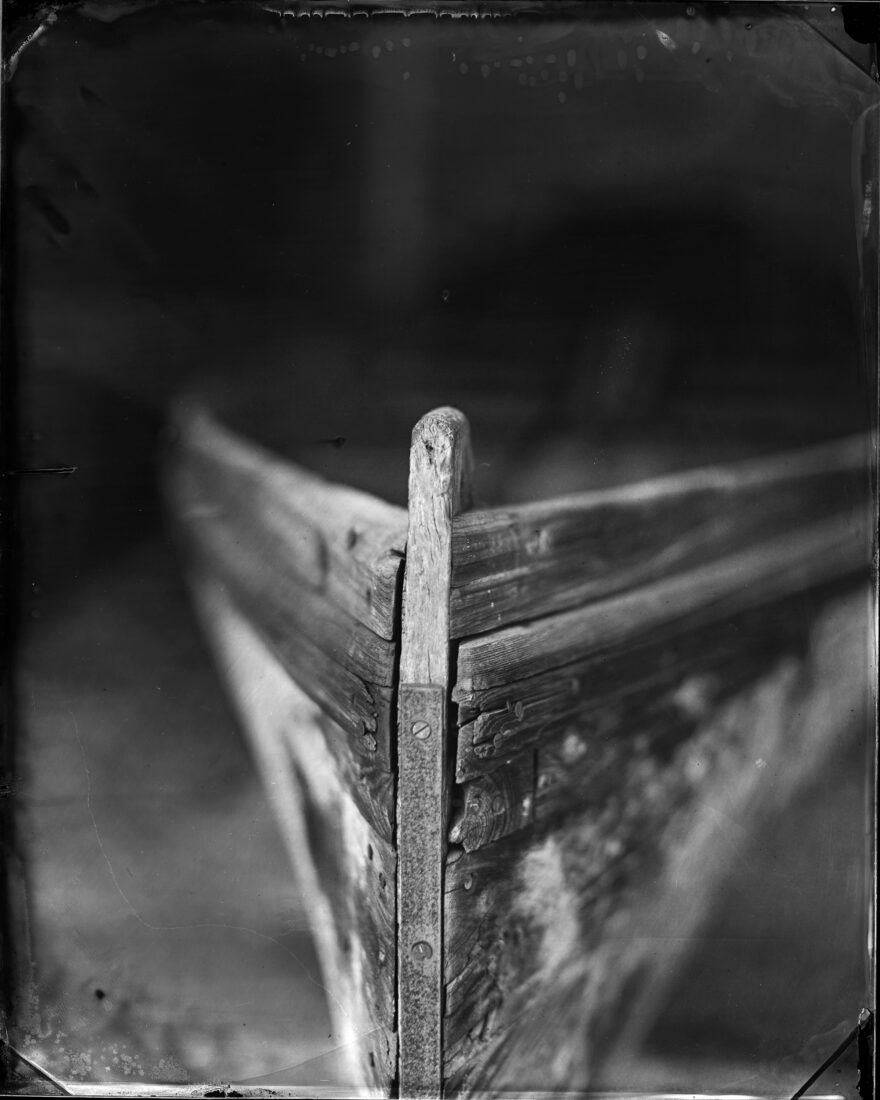A black and white image of an old wood boat