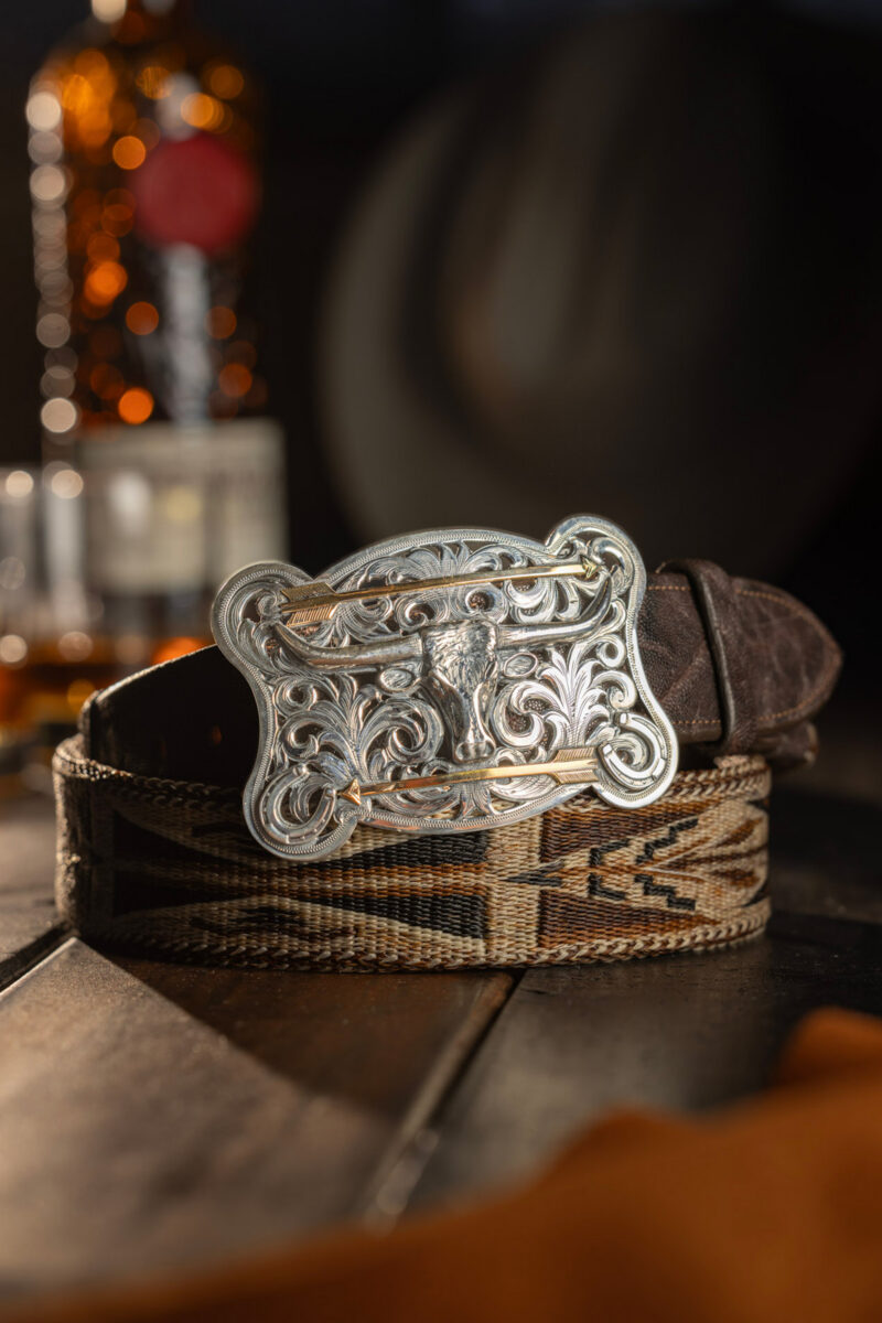 A silver belt buckle on a leather belt