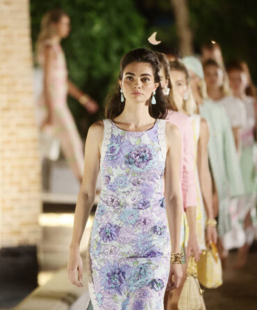 a woman in a purple dress walks the runway