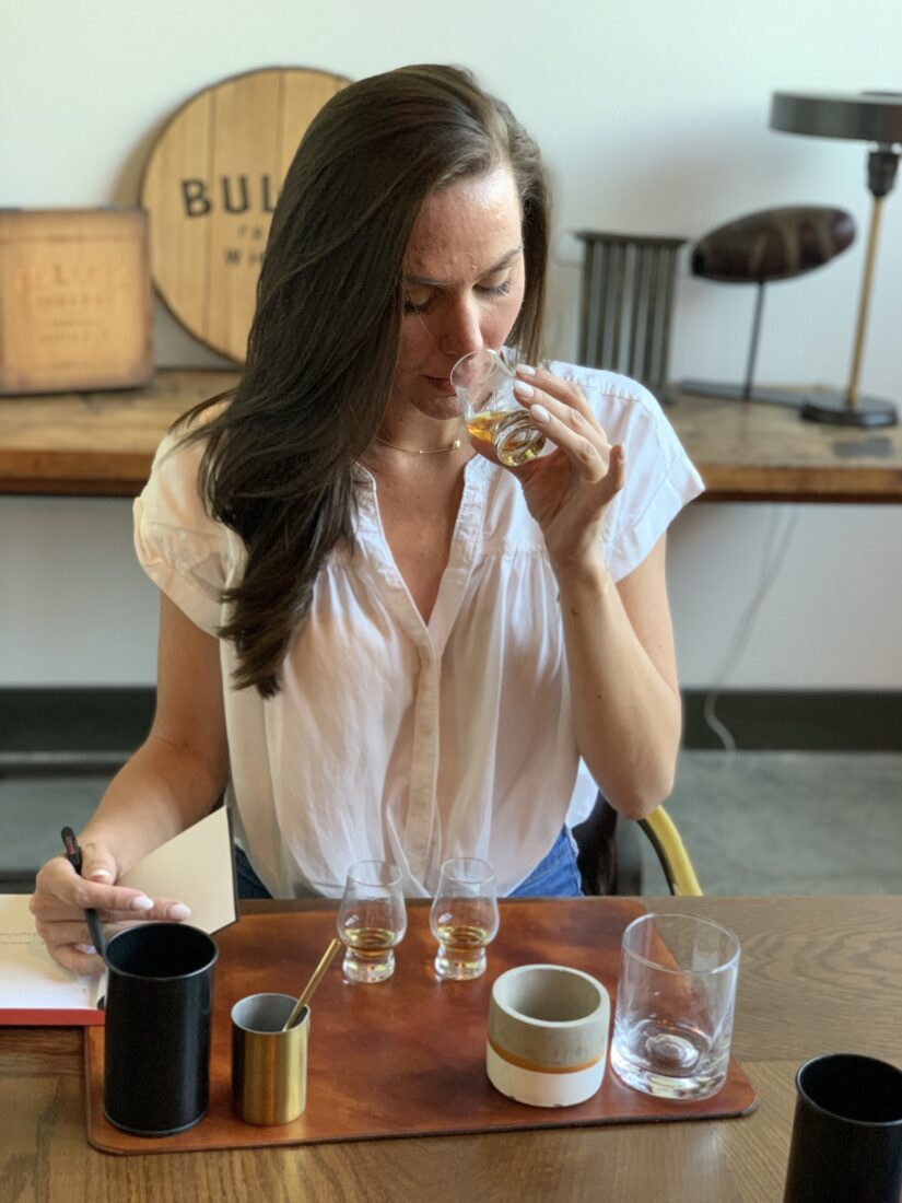 A woman noses a glass of bourbon
