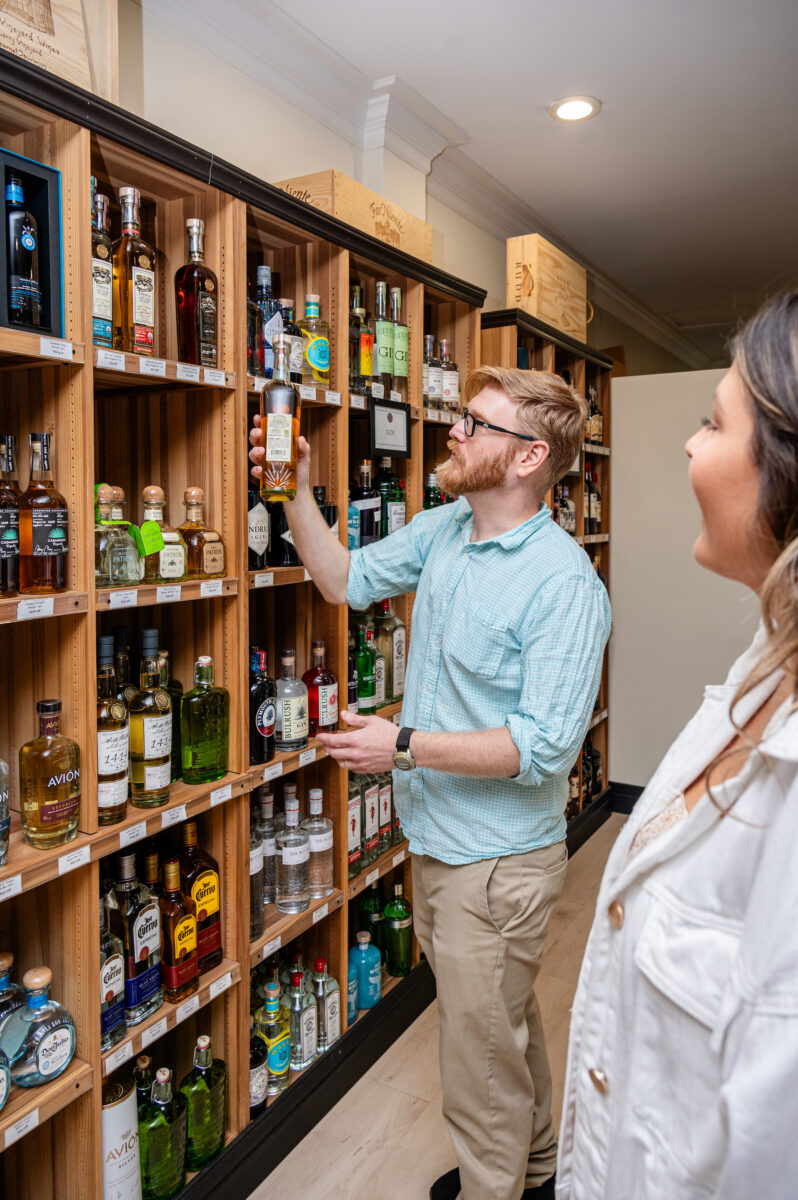 Two people select bottles from a wall