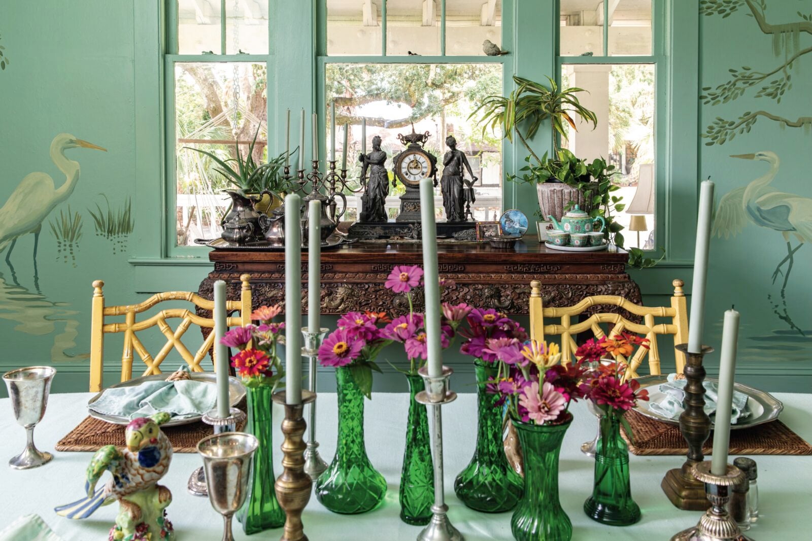 A dining room with teal walls and painted herons