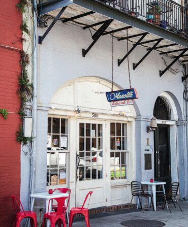 Outside a bar with red chairs and tables on the sidewalk