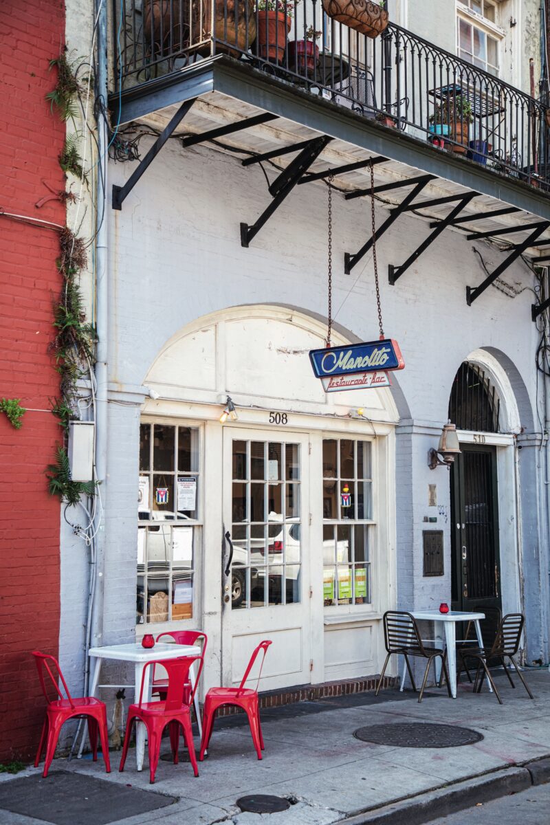 Outside a bar with red chairs and tables on the sidewalk